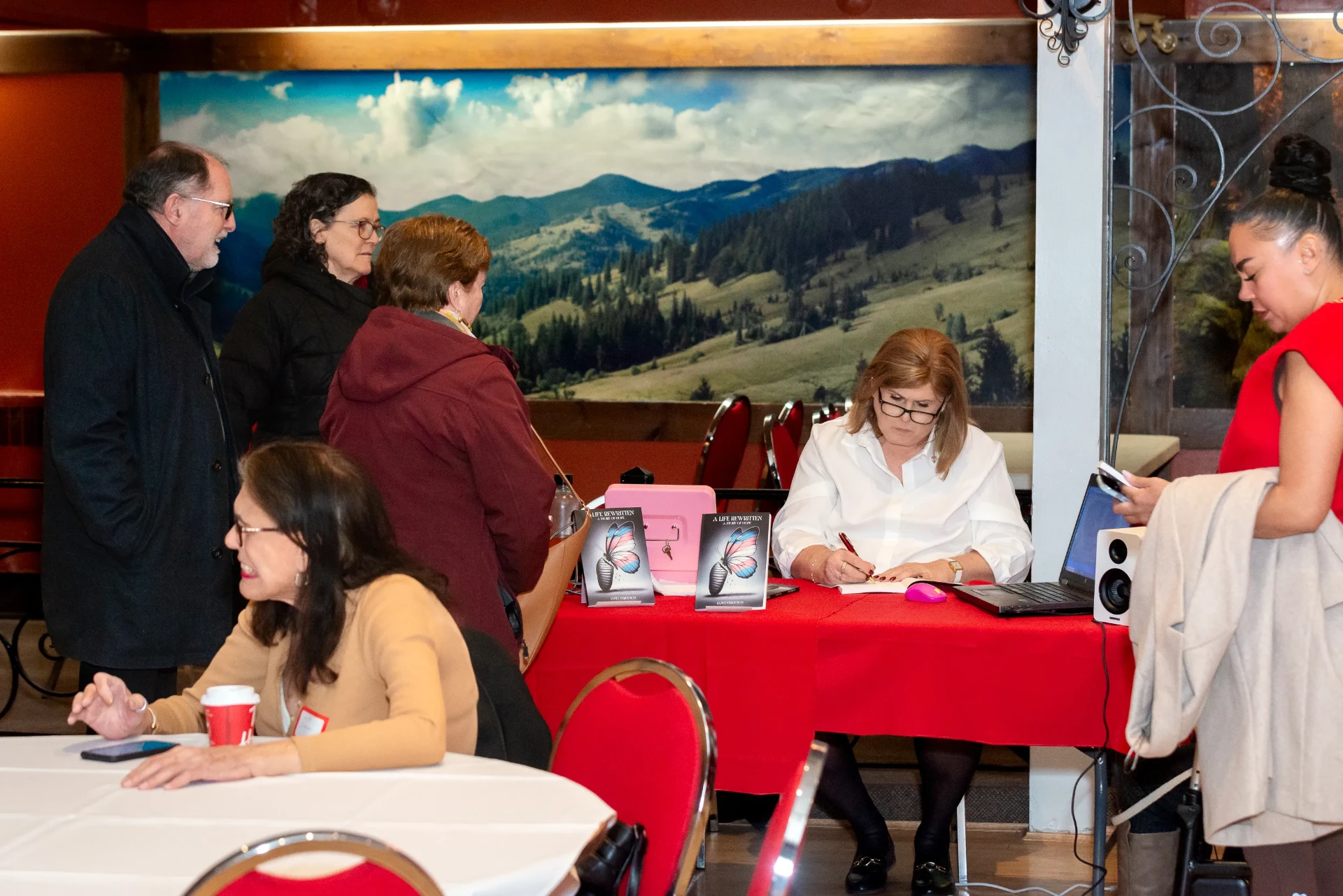 Janet signing books with guests gathered around